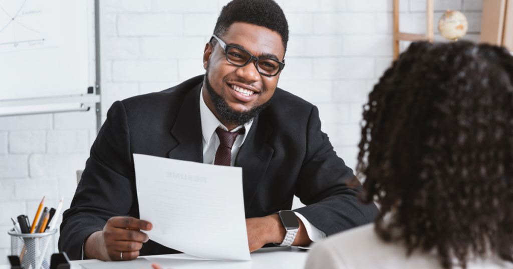 persona di colore con occhiali e cv in mano parla con recruiter
