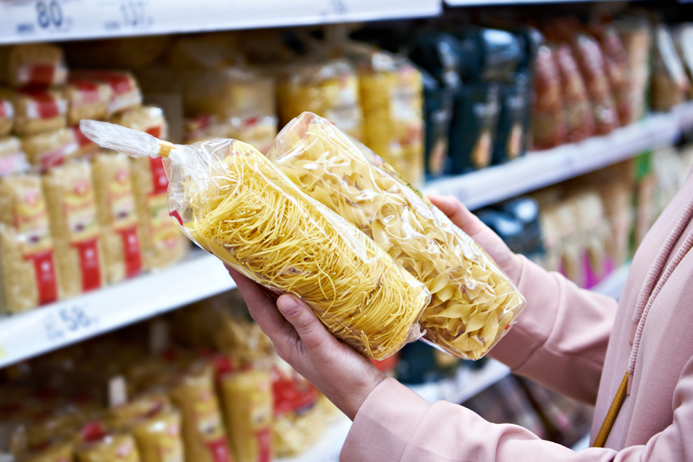 donna che sta guardando a 2 pacchi di pasta nel supermercato negli stati uniti